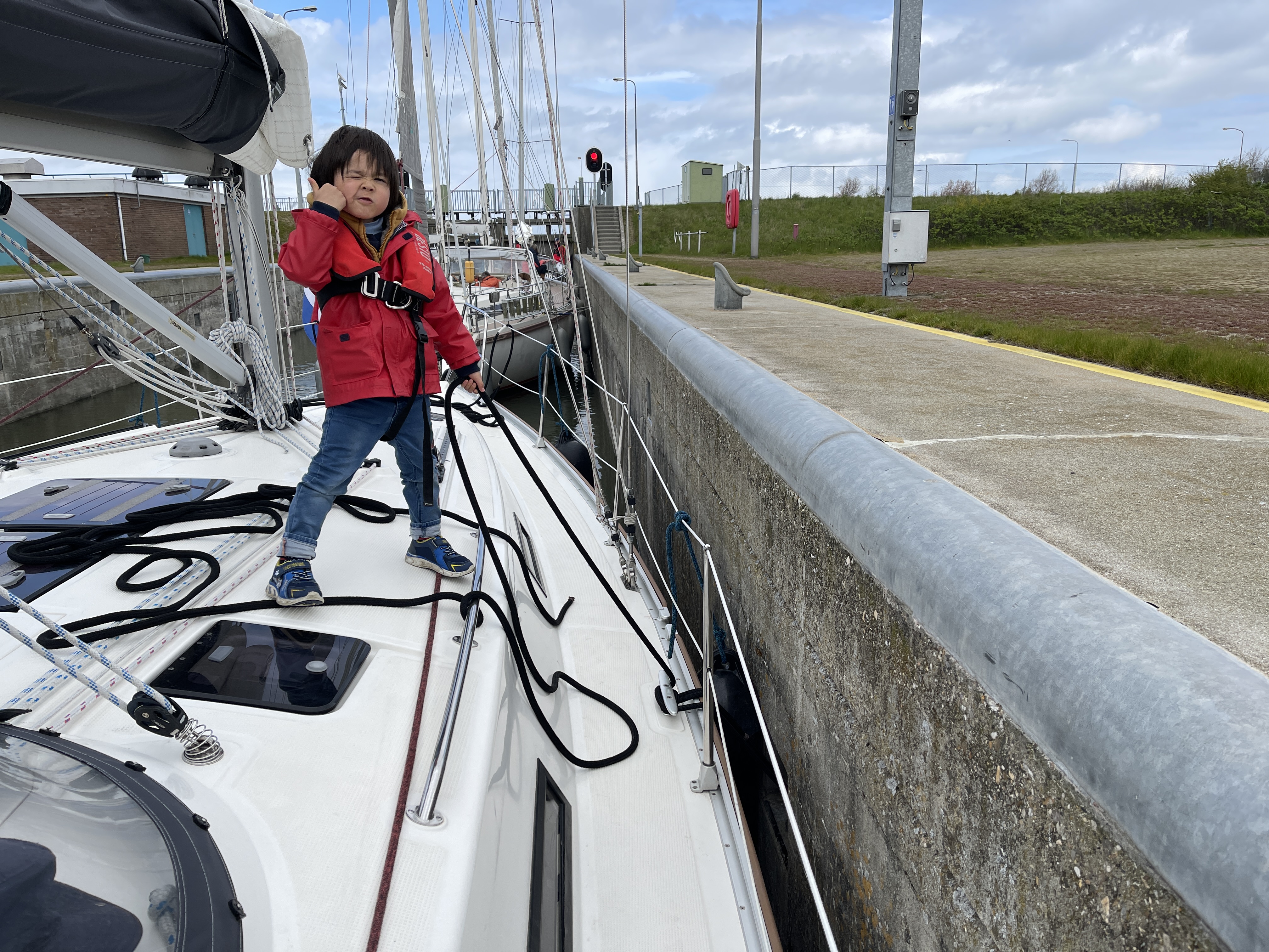 A young crew member handling lines aboard a sailboat in a lock